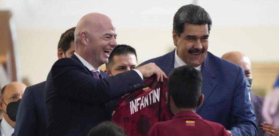 El presidente de la FIFA, Gianni Infantino, sonríe luego que el mandatario venezolano Nicolás Maduro le obsequia una camiseta de la selección.
