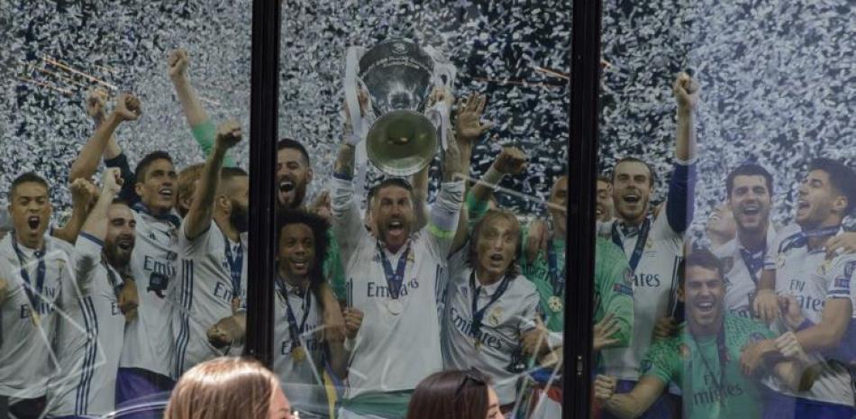Dos mujeres pasan frente a un afiche del Real Madrid, que muestra a sus jugadores festejando la conquista de la Liga de Campeones.