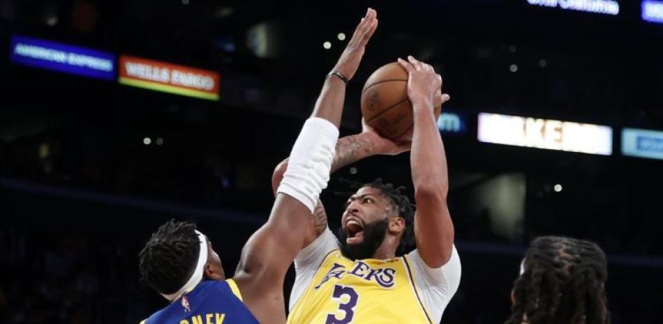 Anthony Davis (3), de los Lakers de Los Ángeles, lanza a canasta ante Kevon Looney (5), de los Warriors de Golden State, en la primera mitad del juego de la NBA.