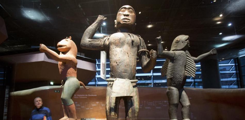 En esta imagen del viernes 23 de noviembre de 2018, un visitante mira estatuas de madera del reino de Dahomey, elaboradas en el siglo XIX en el museo de Quai Branly en París, Francia. En una decisión con posibles consecuencias en museos de toda Europa, Francia mostraba por última vez 26 objetos expoliados en la era colonial antes de enviarlos de vuelta a Benín. (AP foto/Michel Euler, Archivoe)