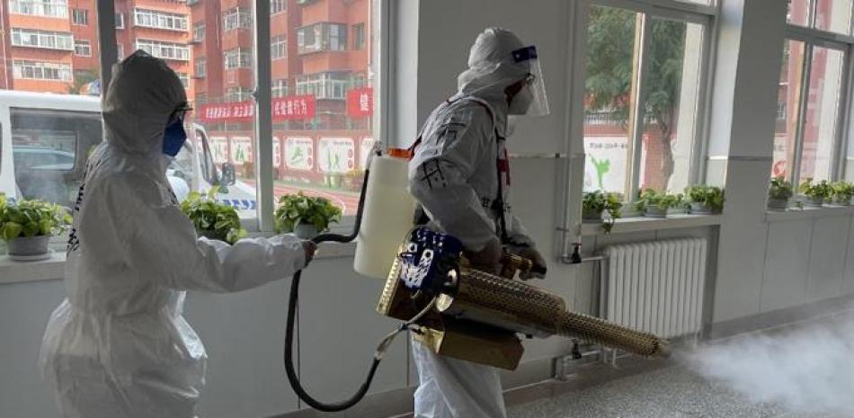 Trabajadores desinfectan un edificio residencial en Lanzhou, en la provincia de Gansu, noroeste de China, el 26 de octubre de 2021. Foto: AFP,