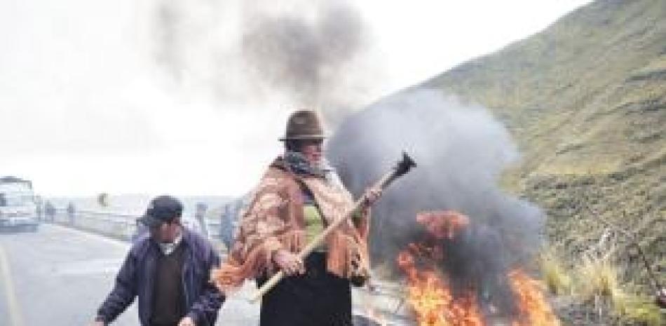 Una mujer indígena se para sobre una barricada. AFP