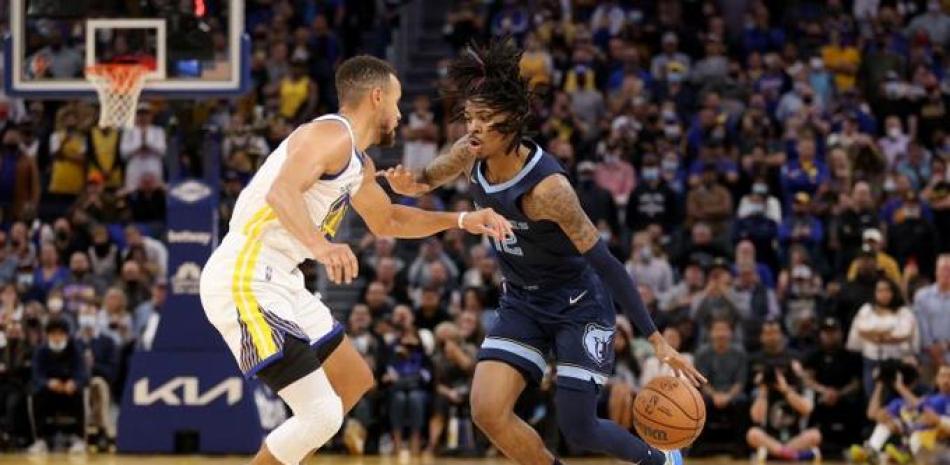 Ja Morant, de los Grizzlies de Memphis, maneja el balón ante la defensa de Stephen Curry, de los Warriors, en acción del partido en el baloncesto de la NBA.