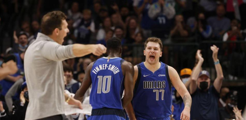 El delantero de Mavericks Dorian Finney-Smith (10) y el guardia Luka Doncic (77) celebran una canasta frente al entrenador de Kings de Sacramento Luke Walton.