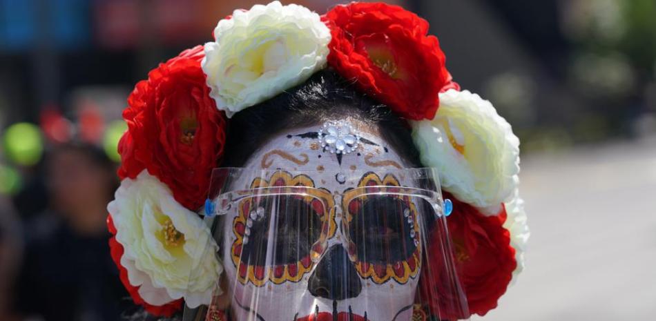Una mujer maquillada como una "Catrina" y con un protector facial posó para una foto durante las festividades del Día de Muertos en la Ciudad de México, el domingo 31 de octubre de 2021. En un desfile se exhibieron altares y obras de arte de todo el país. como los mexicanos honran el Día de Muertos. (Foto AP / Fernando Llano)