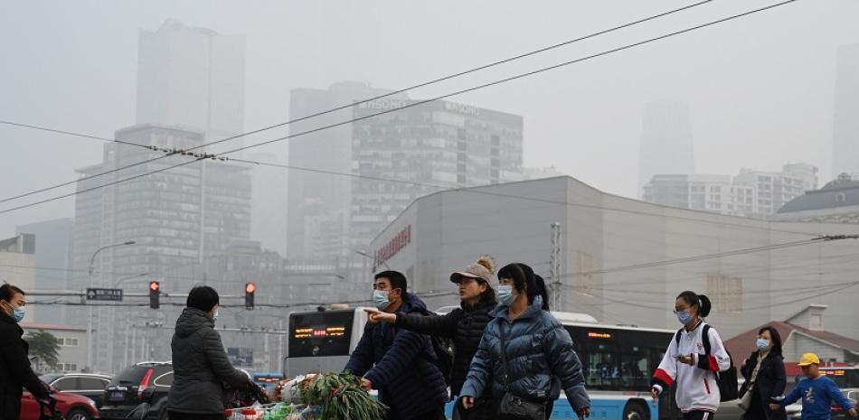 Las personas cruzan una carretera en Beijing el 5 de noviembre de 2021, después de que las carreteras y los patios de recreo de las escuelas fueran cerradas debido a la fuerte contaminación.

Foto: GREG BAKER / AFP