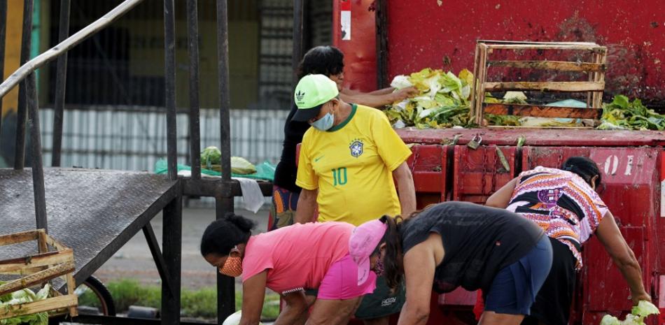 La gente recolecta frutas y verduras desechadas por los vendedores ambulantes en Brasil. Aproximadamente el 55 por ciento de la población del país se enfrenta ahora a la inseguridad alimentaria, y al menos el 15 por ciento vive con una escasez diaria y constante de alimentos. Raimundo Pacco / AFP