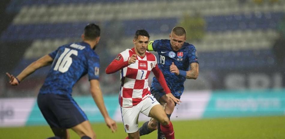 El croata Josip Brekalo supera con el balón a David Hancko, y Juraj Kucka de Eslovaquia en la clasificación del Grupo H a la Copa del Mundo 2022.