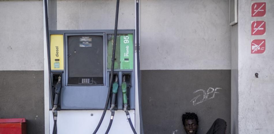 Un hombre yace junto a una bomba de combustible en una gasolinera cerrada mira a la cámara durante el tercer día de huelga general y falta de transporte, en medio de una escasez de combustible en Puerto Príncipe, Haití, el 27 de octubre de 2021.
Ricardo ARDUENGO / AFP