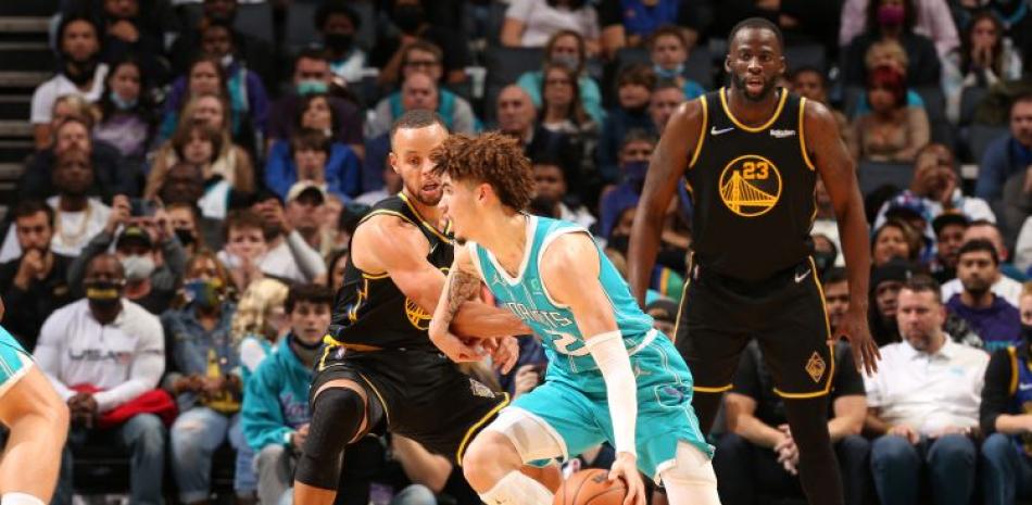 LaMelo Ball, de los Hornets, maneja el balón ante la defensa de Stephen Curry, de los Warriors, en acción del partido de la NBA del domingo por la noche.