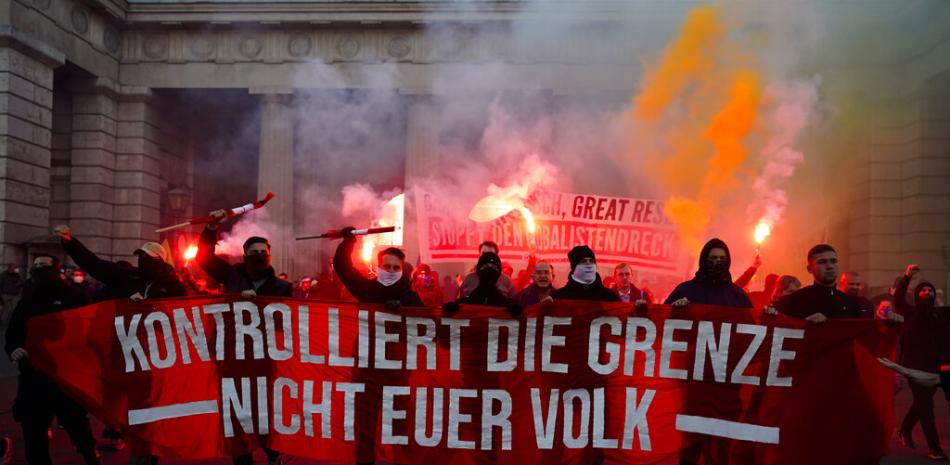 Manifestantes con bengalas gritan consignas durante una manifestación contra las medidas para combatir la pandemia de coronavirus en Viena, Austria, el sábado 20 de noviembre de 2021. La pancarta lee: "Controlen la frontera, no a su gente".

Foto: AP/Florian Schroetter