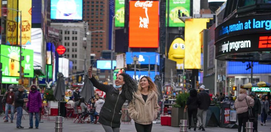 Los peatones posan para fotografías en Times Square, el lunes 15 de noviembre de 2021, en Nueva York. Incluso cuando los visitantes se apiñan nuevamente debajo de las pantallas gigantes en Times Square de Nueva York, las tiendas de souvenirs, restaurantes, hoteles y empresarios dentro del emblemático hito de EE. UU. Todavía se están recuperando de una asombrosa pandemia. (Foto AP / Seth Wenig)