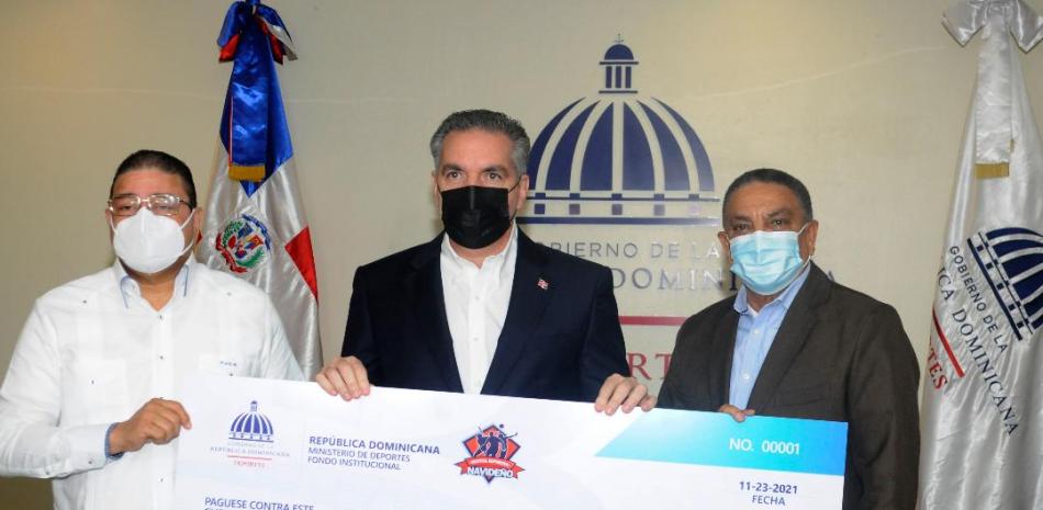 José (Neney) Cabrera, entrega el cheque simbólico de 60 millones de pesos al ministro de Deportes, Francisco Camacho, y al asesor de la Liga Municipal Dominicana (LMD), Mariano Reyes.