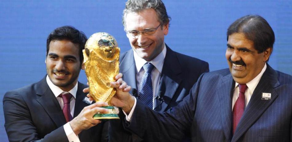 En esta foto de archivo, Mohamed bin Hamad Al-Thani, a la izquierda, presidente del comité de la candidatura para el Mundial de 2022, y el jeque Hamad bin Khalifa Al-Thani, emir de Qatar, sostienen el trofeo del Mundial ante el secretario general de la FIFA, Jerome Valcke, tras el anuncio de que Qatar celebrará el Mundial de 2022, el 2 de diciembre de 2010 en Zúrich, Suiza.rich, Suiza.