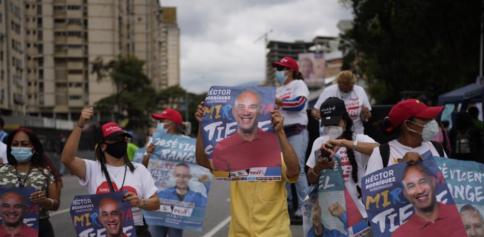 Simpatizantes de los candidatos del partido gobernante sostienen carteles de Héctor Rodríguez y el candidato a la alcaldía de Sucre, José Vicente Rangel, durante un mitin de clausura de campaña en Caracas, el jueves pasado. AP