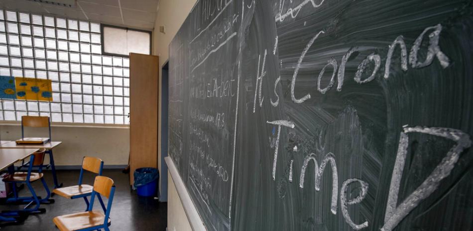 En esta imagen de archivo, los alumnos escribieron "Es la hora del corona(virus)" (en inglés) en la pizarra de un aula vacía, en un instituto de Fráncfort, Alemania, el 13 de marzo de 2020.

Foto: Michael Probst/AP