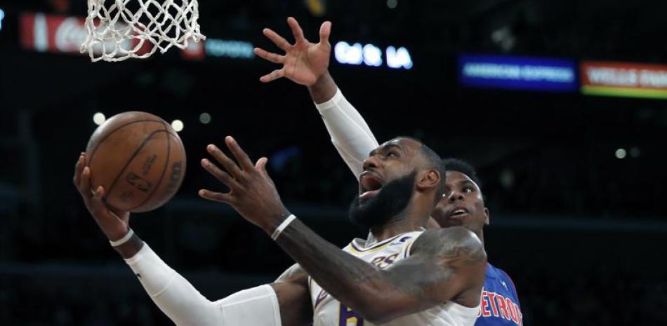 LeBron James, izquierda, de los Lakers de Los Ángeles, intenta encestar en contra del base Hamidou Diallo, de los Pistons de Detroit, en duelo de NBA del domingo 28 de noviembre de 2021, en Los Ángeles.