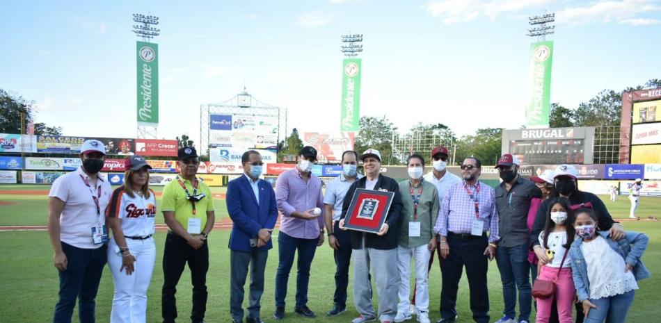 Benbigno -Papo- Romero exhibe la placa de reconocimiento entregada por Gigantes del Cibao durante un emotivo homenaje ofrecido en su honor. Le acompañan ejecutivos del equipo.