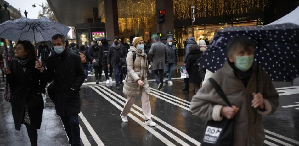 Unas personas con cubrebocas por el coronavirus caminan por una calle de París, el 6 de diciembre de 2021. (AP Foto/Christophe Ena)