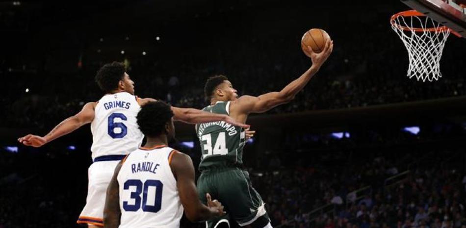 El alero de los Milwaukee Bucks Giannis Antetokounmpo (34) impulsa a la canasta contra el escolta de los New York Knicks Quentin Grimes (6) y el alero Julius Randle (30) durante la segunda mitad de un juego de baloncesto de la NBA en Nueva York, el domingo 12 de diciembre de 2021.