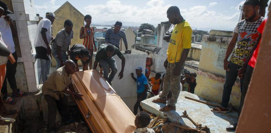 Familiares entierran a una mujer que murió en el hospital por las quemaduras causadas por un camión de gasolina que volcó y explotó, matando a decenas en Cap-Haitien, Haití, el miércoles 15 de diciembre de 2021 (AP Photo / Odelyn Joseph).