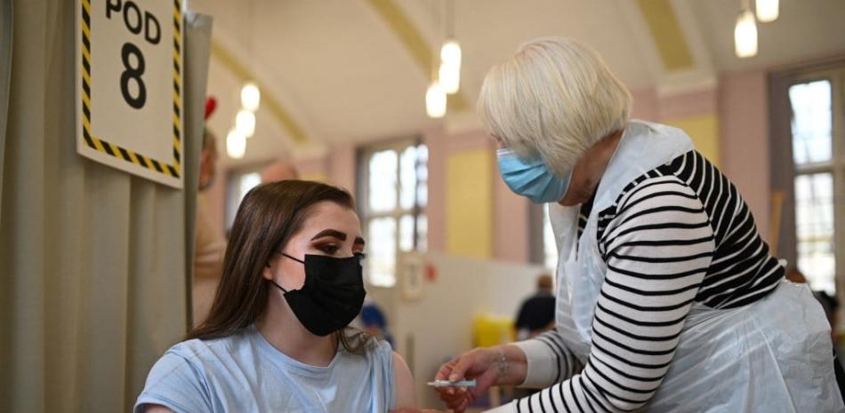 Una mujer recibe una dosis de la vacuna Moderna Covid-19 en el Hospital Babington en Belper el 16 de diciembre de 2021 cuando el Reino Unido intensifica la campaña de refuerzo del país para combatir un "maremoto" de Omicron. Gran Bretaña registró ayer 78,610 casos de coronavirus en laboratorios, el total diario más alto desde que ocurrió la pandemia el año pasado, mientras el país espera con nerviosismo más pruebas de la gravedad y el impacto de la variante.
Oli BUFANDA / AFP