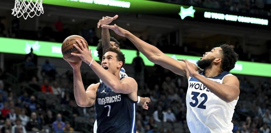 Dwight Powell (7), de los Mavericks de Dallas, se alza rumbo a la canasta ante la marca de Karl-Anthony Towns (32), de los Timberwolves de Minnesota, en la primea mitad del juego de la NBA en Dallas, el martes 21 de diciembre de 2021.