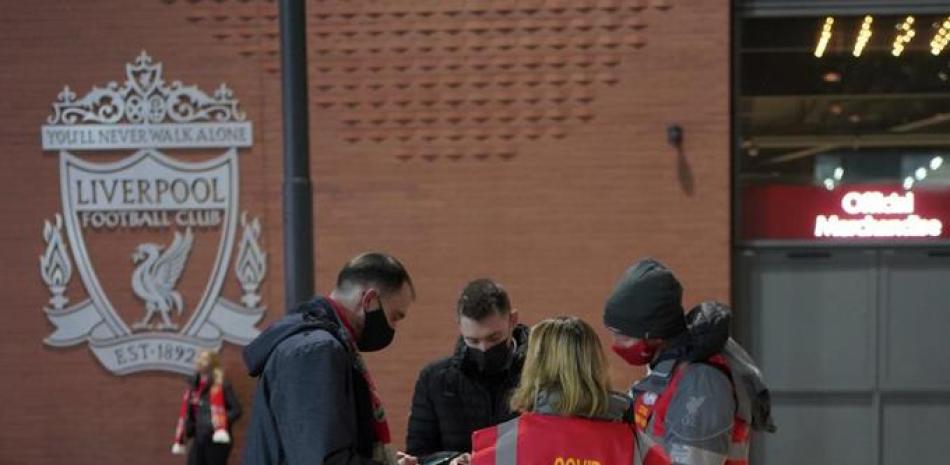 Ujieres examinan los documentos del COVID-19 de hinchas a la entrada del estadio Anfield antes del partido de la Liga Premier inglesa entre Liverpool y Newcastle el 16 de diciembre del 2021.