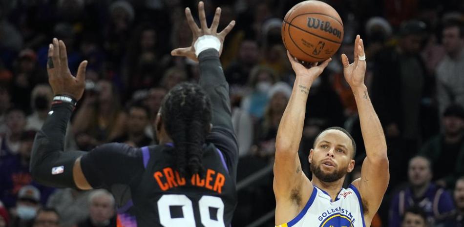 El base de los Warriors de Golden State Stephen Curry lanza el balón sobre el alero de los Suns de Phoenix Jae Crowder en el encuentro del sábado 25 de diciembre del 2021.