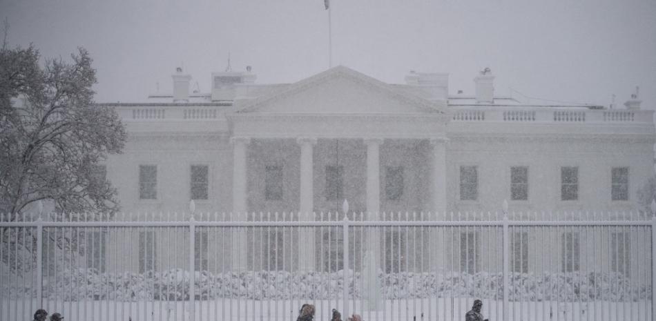Un grupo de mujeres observan a un perro del Servicio Secreto y a su adiestrador haciendo un barrido de seguridad frente a la Casa Blanca durante una tormenta de nieve en Washington, DC el 3 de enero de 2022. 
Foto: ROBERTO SCHMIDT / AFP