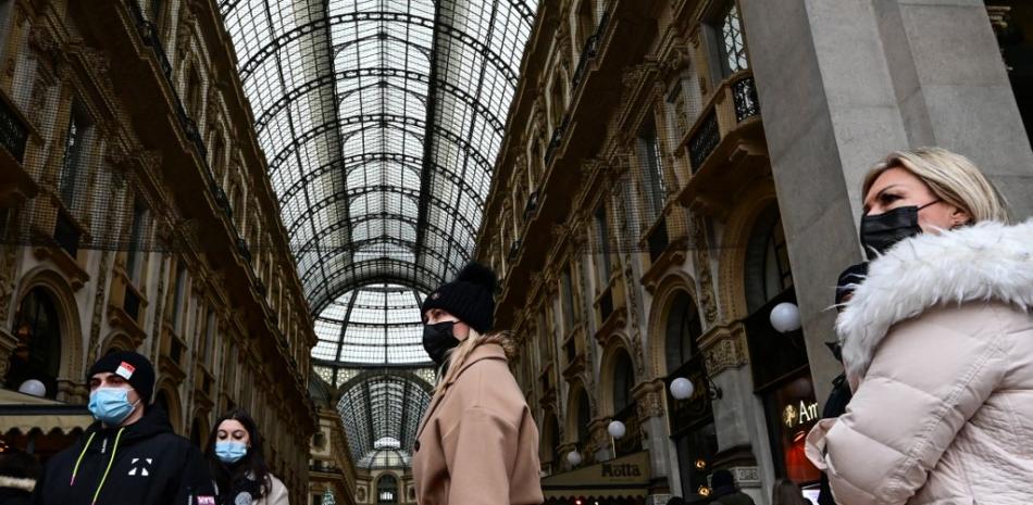 Turistas con máscaras protectoras caminan frente a una entrada de la galería comercial "Galeria Vittorio Emanuele II" cerca de la plaza Duomo en el centro de Milán el 3 de enero de 2022.
Foto: Miguel MEDINA / AFP
