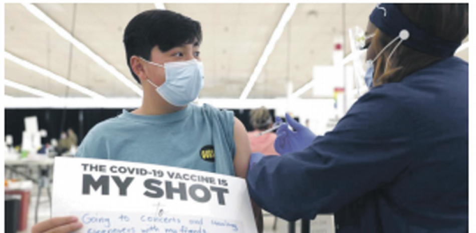Lucas Kittikamron-Mora, de 13 años, muestra un cartel en apoyo a la vacuna contra el COVID-19. AP