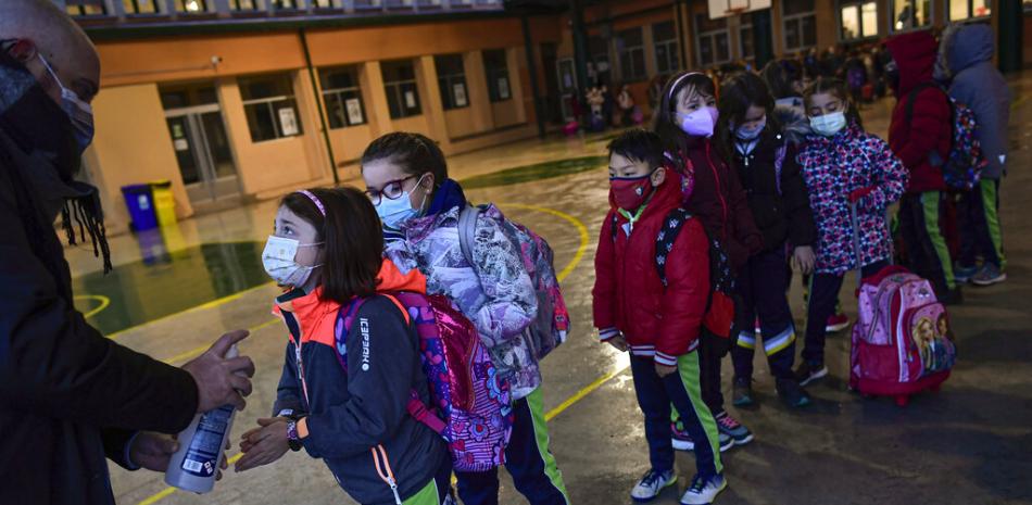 Un grupo de alumnos con mascarilla para prevenir contagios de coronavirus se desinfectan las manos mientras esperan en fila para entrar en la escuela Luis Amigo tras las vacaciones de Navidad, en Pamplona, en el norte de España, el lunes 10 de enero de 2021.

Foto: AP/Álvaro Barrientos