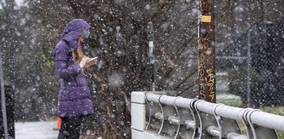 Bridget Step revisa sus mensajes en Atlanta mientras cae nieve, el domingo 16 de enero de 2022. (Foto AP/Ben Gray)