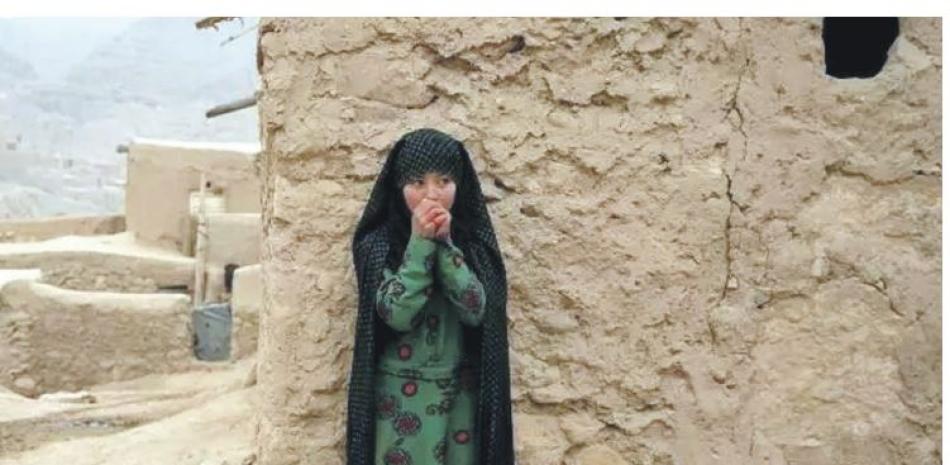 Niña afgana frota sus manos tras cargar tarros de agua hasta su aldea en Balucha. 14 de diciembre de 2021.. AP