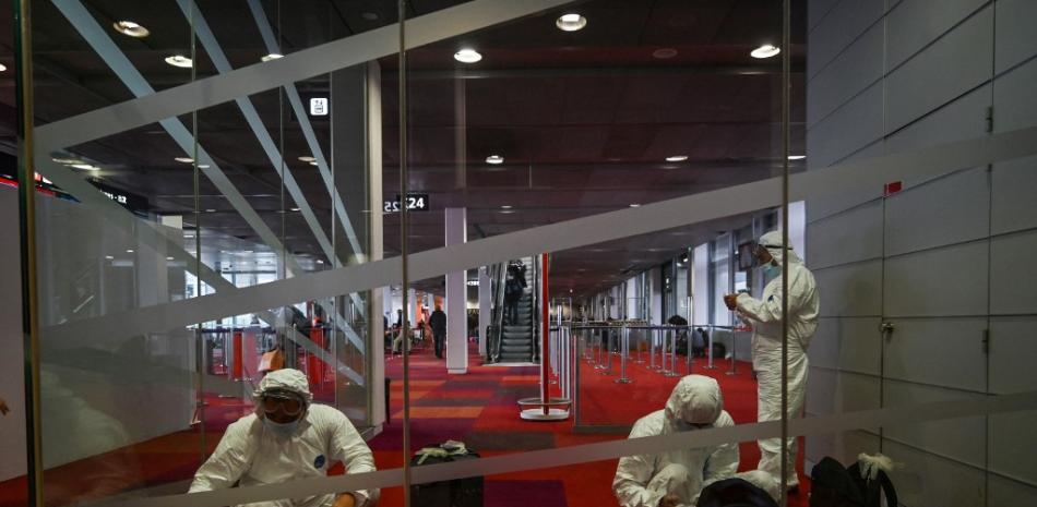 Esta foto tomada el 17 de enero de 2022 muestra a pasajeros chinos con equipo de protección personal completo mientras esperan su vuelo a Shanghái en el aeropuerto Roissy-Charles de Gaulle, en las afueras de París.
HÉCTOR RETAMAL / AFP