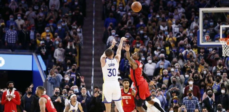 Stephen Curry, de los Warriors, se eleva para anotar el canasto ganador en el partido del viernes frente a los Rockets de Houston.