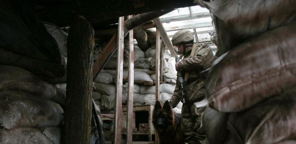 Un militar de las Fuerzas Militares de Ucrania y su perro ingresan a un refugio en primera línea con los separatistas respaldados por Rusia cerca de la aldea de Zolote, en la región oriental de Lugansk, el 21 de enero de 2022. Anatolii STEPANOV / AFP