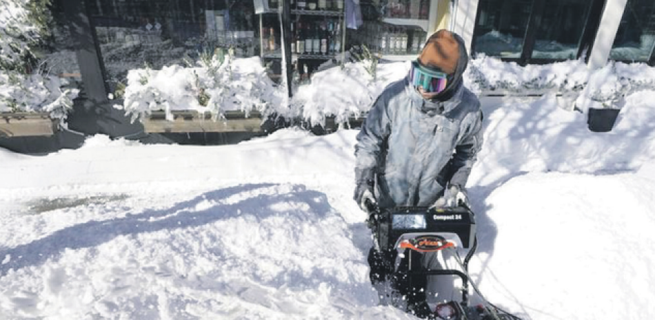 Brandon Winn quita la nieve de una acera, ayer 30 de enero de 2022, en Scituate, Massachusetts. Ráfagas de viento y gélidas temperaturas sumergieron la costa este de EEUU en una helada profunda . AP
