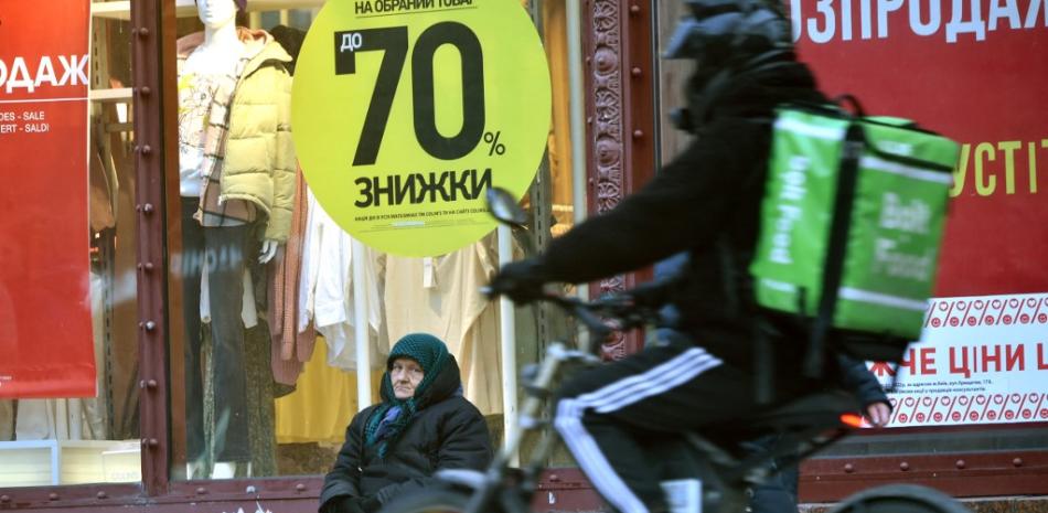 Una anciana vende flores frente a un escaparate con un cartel que dice "Descuentos del 70%" en el centro de la capital ucraniana de Kiev el 2 de febrero de 2022. El riesgo de una invasión rusa aún no ha causado consecuencias económicas catastróficas, pero es ya está teniendo impacto, congelando proyectos y asustando a algunos inversionistas.

Serguéi SUPINSKY / AFP