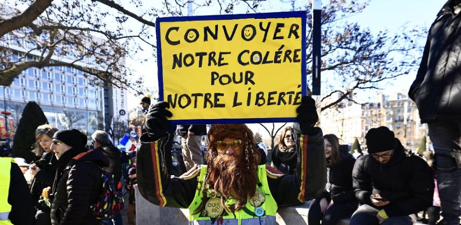 Un manifestante que lleva un chaleco amarillo sostiene un cartel que dice "Transmitamos nuestra ira por nuestra libertad" mientras se reúne con otros manifestantes en la Place d'Italie en París el 12 de febrero de 2022 como convoyes de manifestantes del "Convoi de la Liberte" llegar a la capital francesa. Foto: Sameer Al-Doumy/AFP.