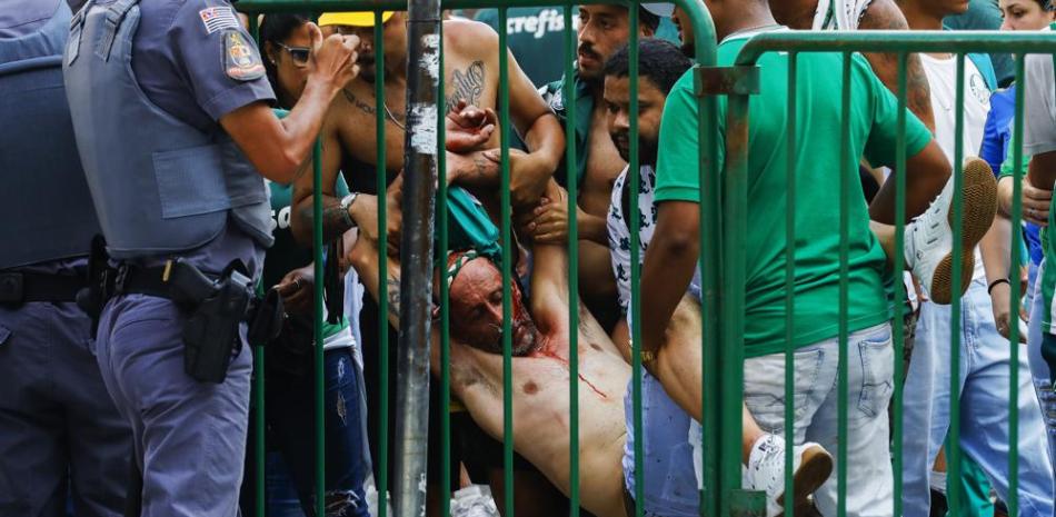Un hincha del Palmeiras es levantado por otros luego de resultar herido en una trifulca en Sao Paulo, el sábado 12 de febrero de 2022 (AP).