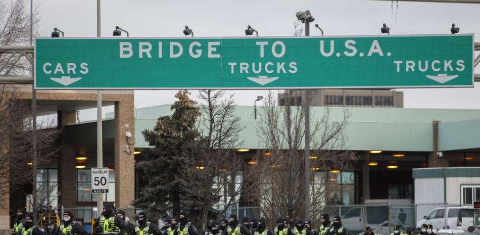 La policía canadiense llega para despejar a los manifestantes y sus vehículos de un bloqueo en la entrada del Puente Ambassador, que estaba bloqueando el flujo de tráfico comercial sobre el puente hacia Canadá desde Detroit, el 12 de febrero de 2022 en Windsor, Canadá. Foto: Cole Burston/AFP.