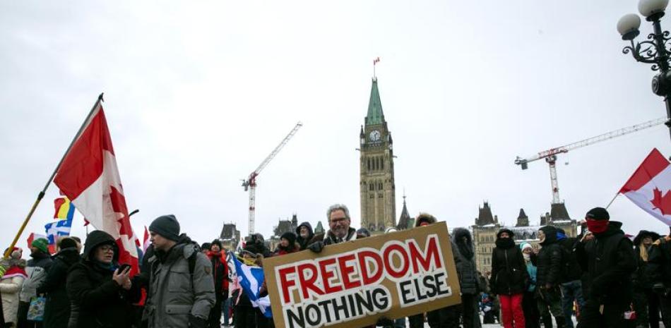 Don Stephens, de 65 años, diseñador gráfico retirado, sostiene un cartel ante el Parlamento para apoyar a los camioneros reunidos para protestar contra las órdenes de vacunación y otras restricciones contra el COVID-19 en Ottawa, Ontario, el sábado 12 de febrero de 2022. (AP Foto/Ted Shaffrey)