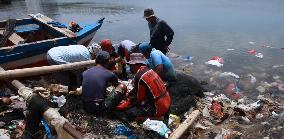 Los pescadores clasifican su captura de una red mientras pescan en aguas contaminadas llenas de desechos plásticos en Bandar Lampung el 21 de febrero de 2022.
PERDIANSYAH / AFP