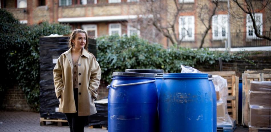 La cofundadora de UpCircle Beauty, Anna Brightman, posa para las fotos junto a los barriles que contienen posos de café usados recogidos de las cafeterías, en su unidad de almacenamiento, en el sur de Londres, el 10 de febrero de 2022. Foto: Tolga Akmen/AFP.