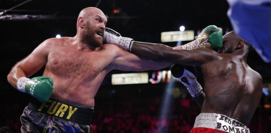 Tyson Fury conecta un golpe en elrostro de Deontay Wilder e la pelea por el cetro pesado que sostuvieron el pasado año.