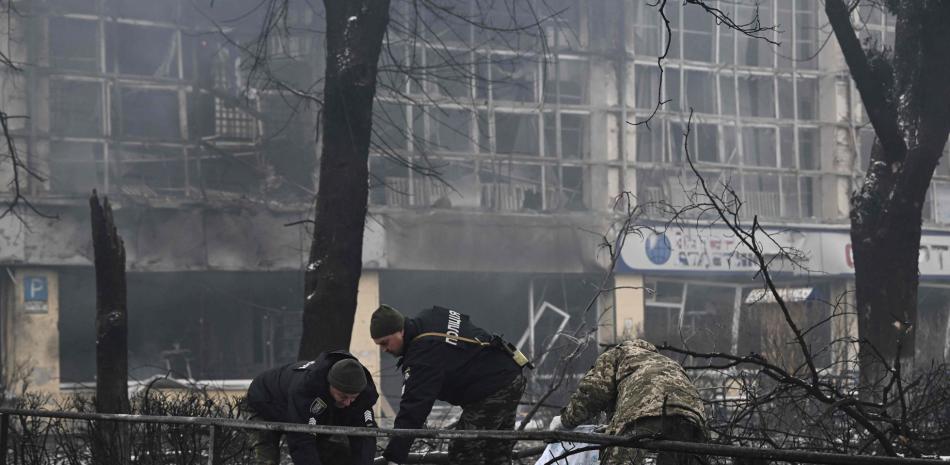 Dos policías cubren el cadáver de una persona que murió el martes en el ataque ruso a la torre de televisión de Kiev, capital de Ucrania. (Foto: Aris Messinis, AFP).