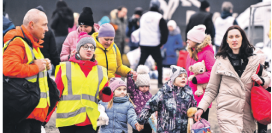 Voluntarios ayudan a las familias ucranianas cuando llegan a Polonia, en el cruce fronterizo de Medyka. AFP/