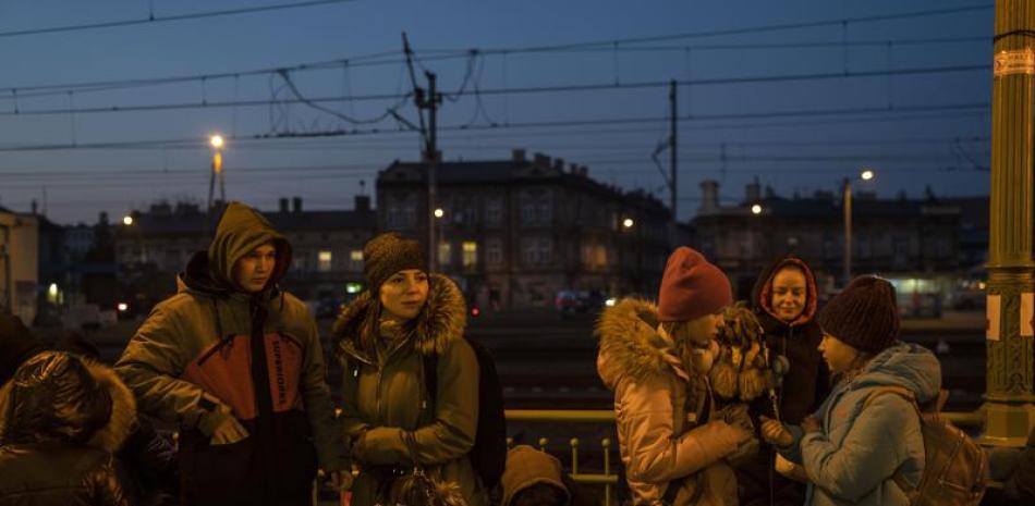 Un grupo de personas que huyeron de la guerra esperan en la estación de tren de Przemysl, sureste de Polonia, el domingo 13 de marzo de 2022. (Foto AP/Petros Giannakouris)